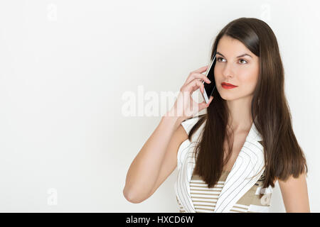 Ritratto di un positivo business donna parlare su un telefono contro uno sfondo bianco Foto Stock