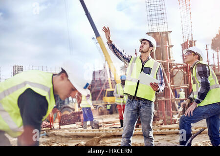 Lavoratori edili parlando al sito in costruzione Foto Stock