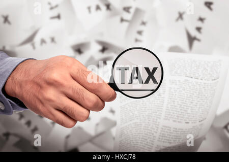 Mano di Business cercando parola fiscale con lente di ingrandimento sulla carta Foto Stock
