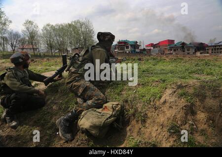 Srinagar Kashmir. 28 Mar, 2017. Esercito indiano troopers prendere posizione come il fumo esce da una casa residenziale durante uno scontro a fuoco nel villaggio di Durbugh Chadoora del distretto di Budgam, circa 22 km a sud di Srinagar city, la capitale estiva del Kashmir, 28 marzo 2017. Almeno tre giovani sono stati uccisi e 13 altri feriti martedì dopo le forze governative hanno sparato su manifestanti in prossimità di un gunfight sito nella irrequieta Kashmir, la polizia ha detto. Credito: Javed Dar/Xinhua/Alamy Live News Foto Stock