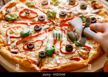 Close up per affettare la deliziosa pizza pizza con taglierina Foto Stock