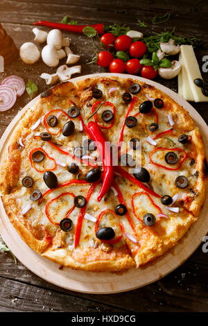 Pizza di formaggio fresco con pepe rosso e gli ingredienti sul tavolo di legno Foto Stock