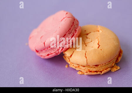 Due amaretti arancione e rosa su sfondo viola, extreme close up Foto Stock