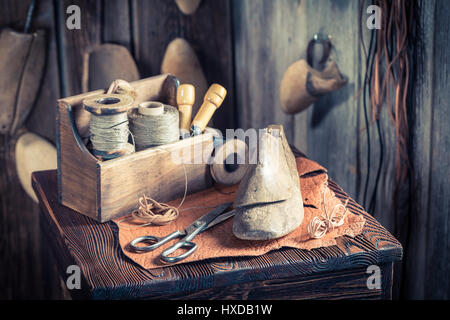 Cobbler piccolo luogo di lavoro con strumenti, scarpe e lacci Foto Stock