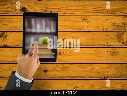 Composito Digitale di mano toccando tablet mostra prenota pila con Apple sulla tabella di colore giallo Foto Stock