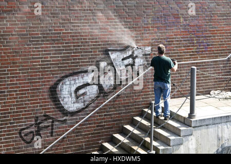 L'uomo elimina graffiti da un muro, rimosso graffiti su un flusso |, Mann entfernt Graffiti un einer Mauer |uomo rimosso graffiti su un muro| Foto Stock