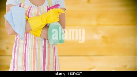 Digital composito della donna in grembiule con il detergente contro sfocata giallo pannello di legno Foto Stock