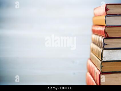 Digital composito della pila di libri Contro sfocata grigio sul pannello di legno Foto Stock