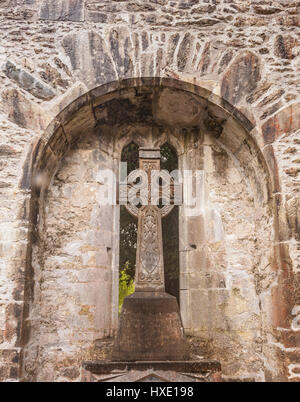 Croce celtica nell'arcata delle rovine di un castello in Irlanda Foto Stock