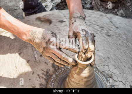 Primo piano di una ruota in ceramica con argilla coperto le mani Foto Stock