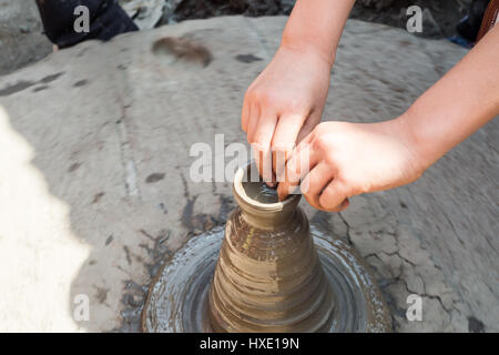 Primo piano di una ruota in ceramica con argilla coperto le mani Foto Stock