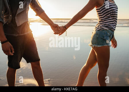 Ritagliato colpo di giovane uomo e donna tenendo le mani e piedi sulla riva. Foto Stock