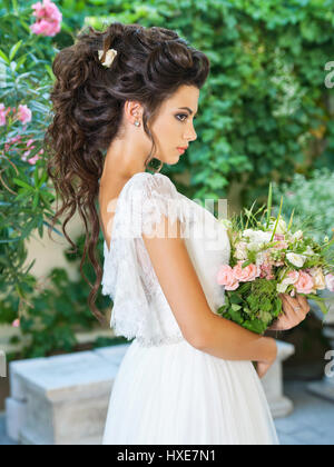 Bella sposa in un abito da sposa con un bouquet Foto Stock