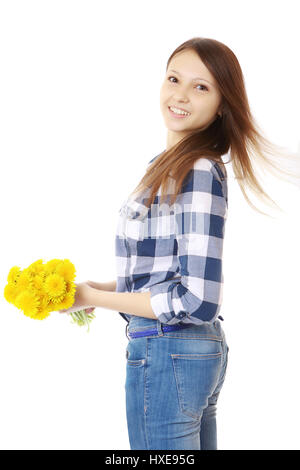Ragazza vestita in jeans e una maglietta scozzese, detiene un giallo fiori selvatici. Ragazza con bouquet di tarassaco. Una persona, aspetto caucasico, marrone capelli, te Foto Stock