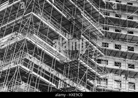 La vita moderna casa è in costruzione, il blocco di appartamenti facciata frammento con strutture di ponteggio, foto in bianco e nero Foto Stock