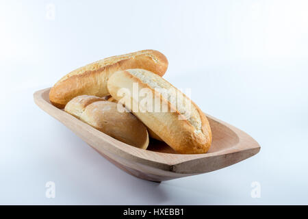 Mini-baguette francesi il pane su una rettangolare ciotola di legno con sfondo bianco Foto Stock