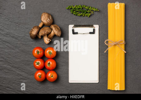 Italiano Foto di spaghetti ricetta. Fermo mockup sul tavolo di cucina circondato con prodotti. Foto Stock