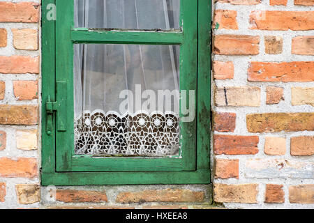 Dipinto di verde vecchia finestra rotta con il bianco tende di pizzo. Dettaglio delle decorazioni vintage Foto Stock