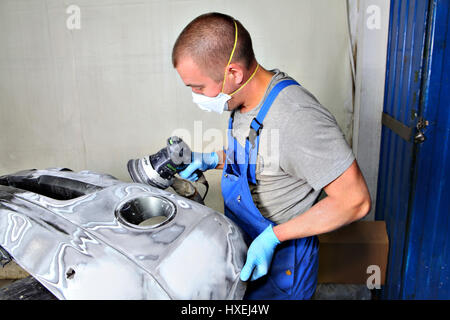 San Pietroburgo, Russia - 26 Giugno 2014: Stazione di servizio, pittura opere di corpo, lavorando in un respiratore di protezione sul suo volto, lucidi per paraurti anteriore o Foto Stock