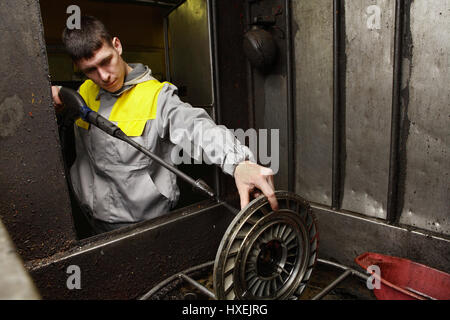 San Pietroburgo, Russia - 23 dicembre 2011: stazione di servizio, officina di riparazione motore, un giovane meccanico automatico pulisce il disco della frizione, la rondella a pressione. Foto Stock