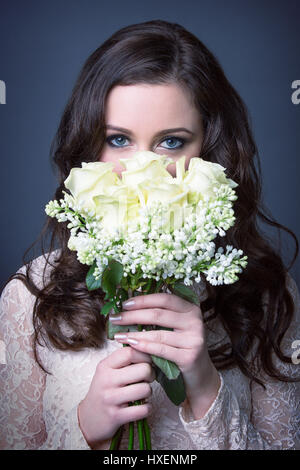 Ragazza con un mazzo di fiori nella parte anteriore del suo viso Foto Stock