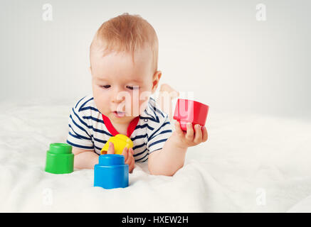 Nove mesi di età bambino giacente sul letto su coltre bianca Foto Stock