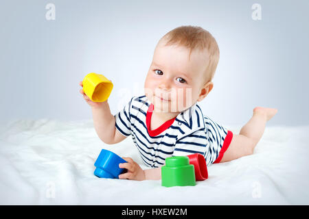 Nove mesi di età bambino giacente sul letto su coltre bianca Foto Stock