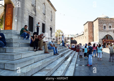 Turistici locali e rilassarsi al di fuori dell'ingresso principale della nuova moschea (Yeni Cami). La moschea si trova presso il Golden Horn all'estremità meridionale della Foto Stock