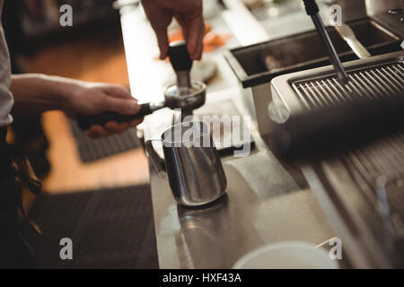 Immagine ritagliata di maschio barista timbratura caffè nella caffetteria Foto Stock