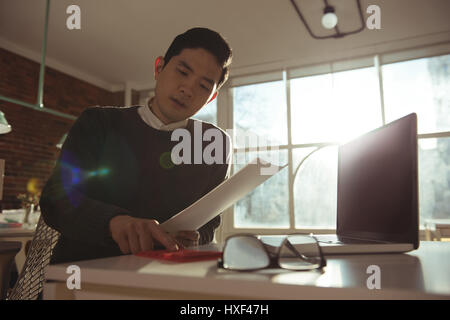 Executive maschio utilizzando la calcolatrice sulla scrivania in ufficio Foto Stock
