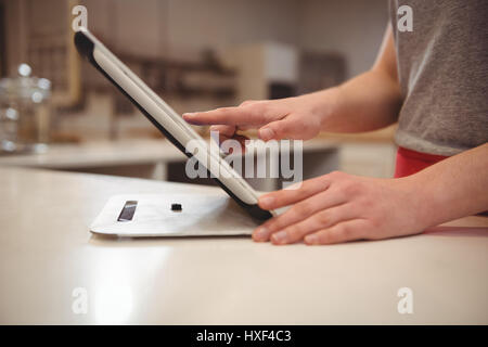 Close-up del barista femmina con tavoletta digitale nel coffee shop Foto Stock
