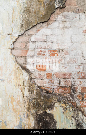 Rotto il vecchio e sporco e muro intonacato rivelando il vecchio muro di mattoni. Foto Stock