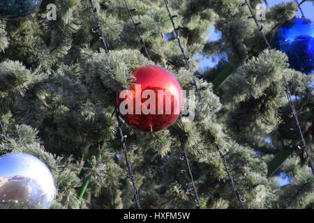 Decorazioni Anno nuovo albero. Tinsel e giocattoli, le sfere e le altre decorazioni di Natale sulla struttura ad albero di Natale in piedi in aria aperta. Foto Stock