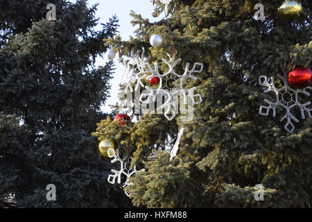 Decorazioni Anno nuovo albero. Tinsel e giocattoli, le sfere e le altre decorazioni di Natale sulla struttura ad albero di Natale in piedi in aria aperta. Foto Stock