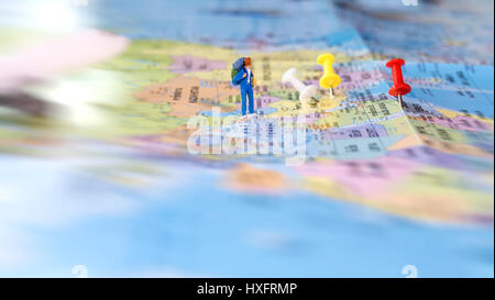 Messa a fuoco selettiva delle figurine in miniatura di lonely giovani viaggiatori con zaino camminando sulla grande mappa con il pin e l'aereo. Il concetto di viaggio Foto Stock