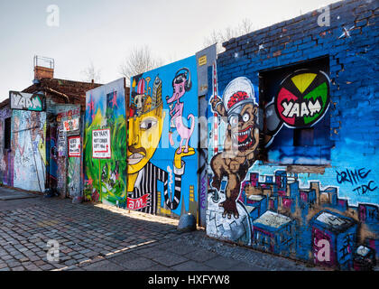 Berlino,Friedrichshain. Vecchia entrata a YAAM, giovane africano il mercato dell'arte con il segno e la parete ricoperta in una colorata arte di strada Foto Stock