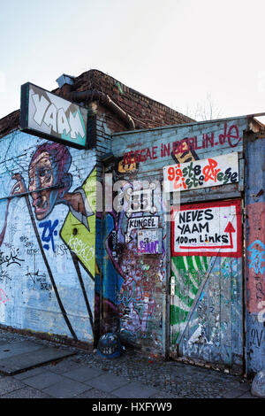 Berlino,Friedrichshain. Vecchia entrata a YAAM, giovane africano il mercato dell'arte con il segno e la parete ricoperta in una colorata arte di strada Foto Stock