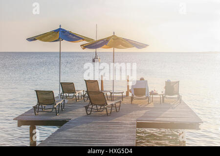 Matura in seduta sdraio su una tavola di legno boatdeck rilassarsi e godersi il tramonto dei Caraibi Foto Stock