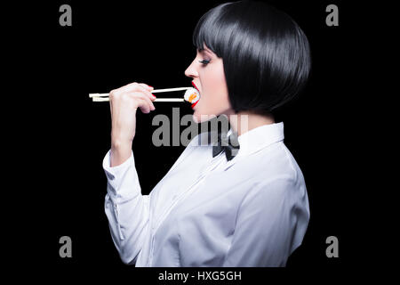 Giovane donna in parrucca mangiare sushi da bacchette. Ruolo di sushi su  tavola di legno Foto stock - Alamy