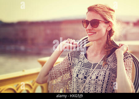 Giovane donna turistica azienda hat camminando sul Ponte vintage ritratto all'aperto Foto Stock