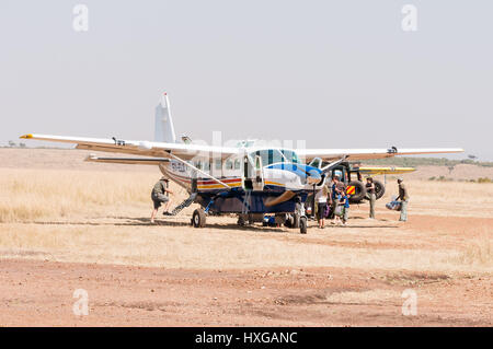 Piano Cessna in attesa sulla pista polverosa mentre i passeggeri aerei di carico, il Masai Mara Foto Stock