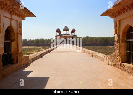 Una passerella di pietra al sito storico di Jal Mahal nel Rajasthan campagna india sotto un cielo blu Foto Stock