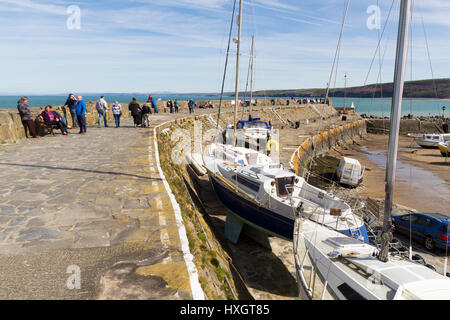 La gente seduta sulla parete del mare nella piccola cittadina turistica di nuova banchina in Galles Foto Stock