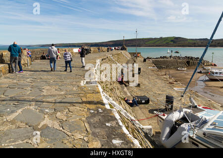 La gente seduta sulla parete del mare nella piccola cittadina turistica di nuova banchina in Galles Foto Stock