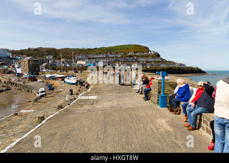 La gente seduta sulla parete del mare nella piccola cittadina turistica di nuova banchina in Galles Foto Stock