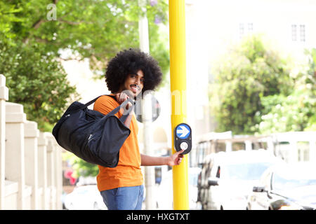 Ritratto di un giovane ragazzo spingendo il pulsante di cross street Foto Stock