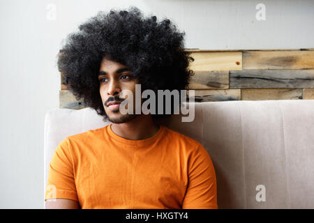 Close up ritratto di una giovane ragazzo nero con afro seduti a casa pensando Foto Stock