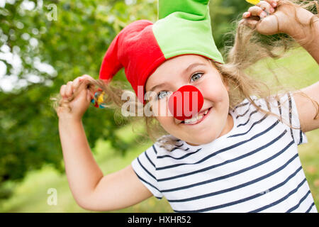 Ragazza in costume da clown con naso rosso divertendosi nel carnevale Foto Stock