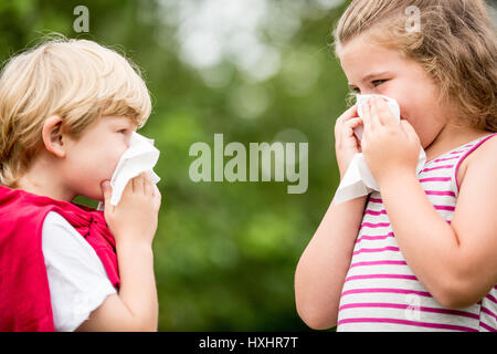I bambini con febbre da fieno o la canna fumaria starnuti e naso di pulizia con il tessuto Foto Stock