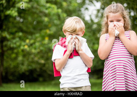I bambini con febbre da fieno o allergia al parco starnuti e utilizzando un tessuto Foto Stock